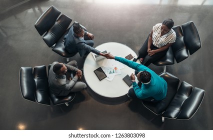 Group Of Business People Sitting And Discussing Statistics During A Sit Down Meeting Taking From Above