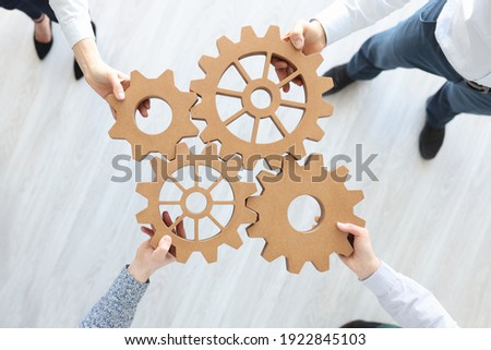 Group of business people stacking wooden gears top view. Teamwork concept