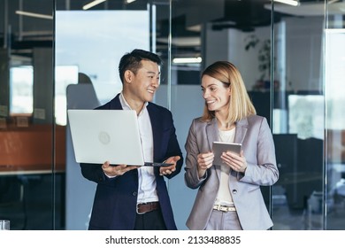 A Group Of Business People Stand In The Hallway And Discuss About Problems In The Company. Person Employees Using Laptop And Digital Tablet In Office. Thoughtful Asian Busy Managers Keeping Gadget