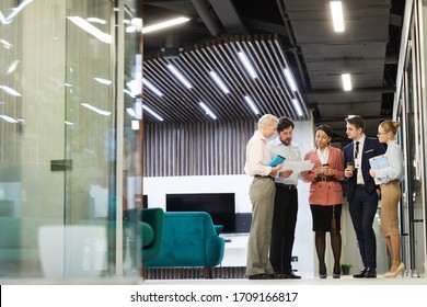 Group Of Business People And Talking To Each Other While Standing At Office Corridor And Waiting For The Beginning Of The Meeting