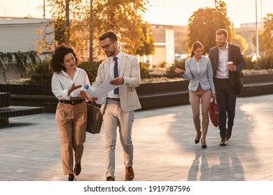 Group Of Business People Walking Outside In Front Of Office Buildings.