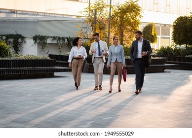 Group Of Business People Walking Outside In Front Of Office Buildings.