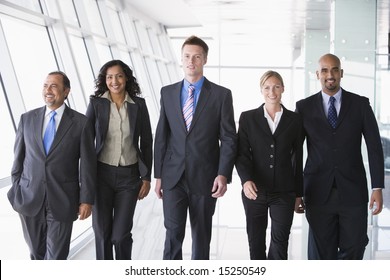 Group Of Business People Walking Through Office Towards Camera