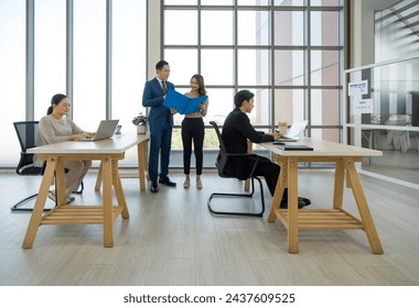 Group of business professional are working in a bright office with large window, table, laptop, and plant. - Powered by Shutterstock