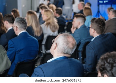 A group of business professionals attentively listening to a speaker at a corporate seminar. People are dressed in formal attire, focusing on the presentation. - Powered by Shutterstock