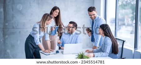 Group of business professionals gather around a desk engaging in a focused discussion holding notebooks and documents during meeting with their executive director at office.