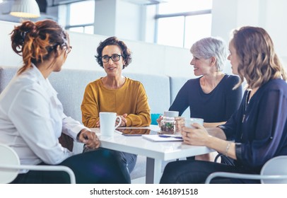 Group Of Business Women Sitting At Table Talking Over A Coffee. Business Team During A Coffee Break In Office.