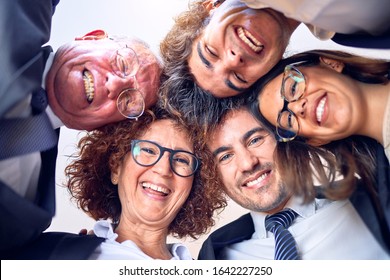 Gruppe von Geschäftsleuten lächelt glücklich und zuversichtlich. Steht mit Lächeln auf Gesicht Umarmung und mit Köpfen zusammen im Büro.