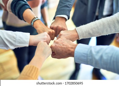 Group of business workers standing bumping fists at the office - Shutterstock ID 1702850695