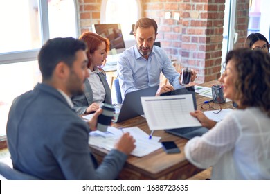 Group Of Business Workers Working Together. Sitting On Desk Using Laptop Reading Documents At The Office