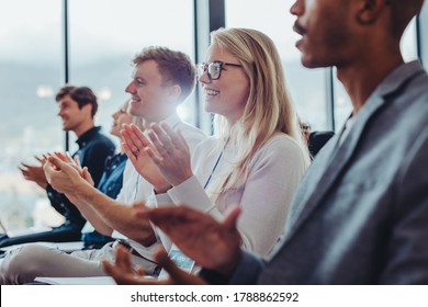 Group Of Businessmen And Businesswomen Sitting In Audience Clapping Hands During A Presentation. Businesspeople Applauding In A Conference.