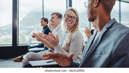 Group Of Businesspeople Applauding Speaker After Conference Presentation. Business Men And Women Sitting In Audience Clapping Hands.