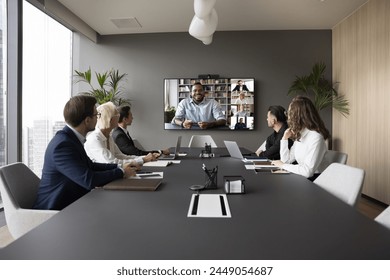 Group of businesspeople gathered in conference room take part in virtual meeting with international corporate partners using video call apps, engaged in online remote negotiations or briefing event - Powered by Shutterstock