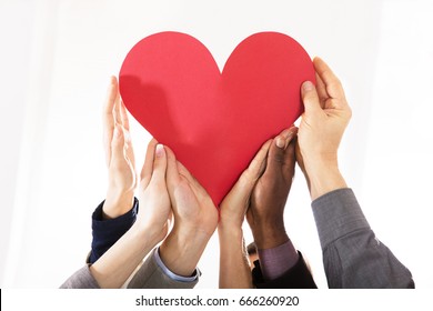 Group Of Businesspeople Hands Holding Red Paper Heart Against White Background