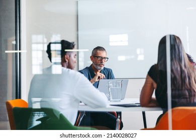 Group of businesspeople having a discussion in a meeting room. Experienced mature businessman leading a meeting in a modern office. Group of creative businesspeople working as a team. - Shutterstock ID 2140028027