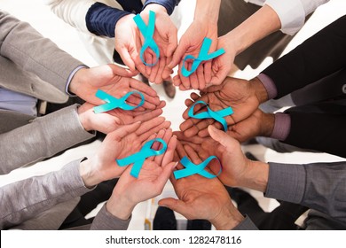 Group Of Businesspeople Holding Teal Ribbons To Support Ovarian Cancer Awareness