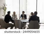 Group of businesspeople negotiating gathered in modern conference room, blurred silhouettes view, meeting behind closed glass doors. Business communication, workflow, decision-making, strategy sharing