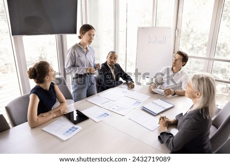 Group of businesspeople, staff members take part in morning briefing conduct by millennial teammate, share opinion, solutions, sales strategy gathered together in modern conference room, above view 商業照片 © 