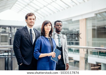 group of businesspeople standing together in office and looking at camera