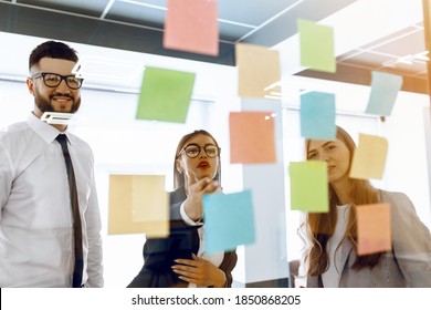 Group Of Businesspeople Teaming Up At Whiteboard During Strategic Session In Bright Modern Office