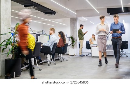 Group of businesswomen and businessmen working in modern office. Busy coworking open space with staff walking and working together. Group of creative men and casual women working in creative agency. - Powered by Shutterstock