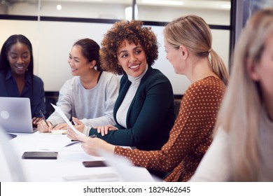 Gruppe von Unternehmerinnen, die an kreativen Treffen am runden Tisch im modernen Büro zusammenarbeiten