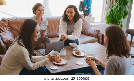 Group Of Businesswomen Working At Laptop Sitting On Sofas In Coffee Shop Having Informal Meeting - Powered by Shutterstock