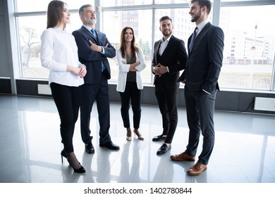 Group Of Busy Business People Concept. Business Team Discussing Work In Office Building Hallway