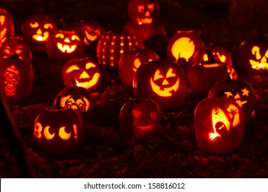 Group of candle lit Halloween pumpkins in park on fall evening