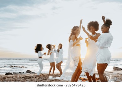 Group of carefree young women toasting wine glasses while dancing and having fun on the beach, having hen party at coastline. Female friends enjoying their vacation - Powered by Shutterstock