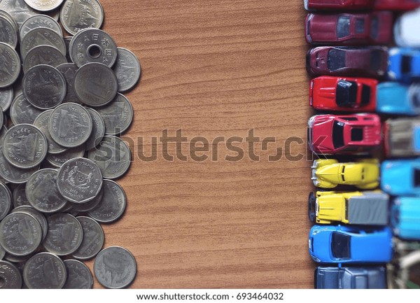 Group of cars and pile coins money with empty wooden\
space in middle 