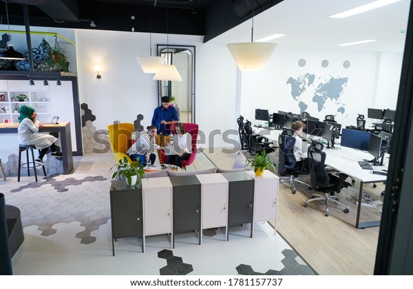 group of casual\
multiethnic business people taking break from the work doing\
different things while enjoying free time in relaxation area at\
modern open plan startup\
office