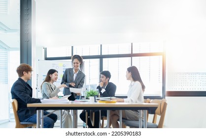 Group of casually dressed asian businesspeople discussing ideas in workspace, Creative professionals gathered at the meeting table for discuss important issues of the new successful startup project. - Shutterstock ID 2205390183