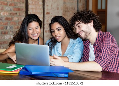 Group of caucasian and latin american students learning with computer indoors at university