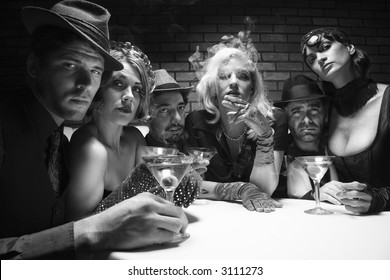 Group of Caucasian prime adult retro males and females sitting at table in lounge looking at viewer.