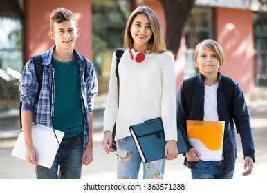 Group of caucasian teens going to school with papers for study 