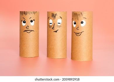 group of characters made from toilet paper rolls with painted face expressing happiness or satisfaction over pink background, emotion group concept, diy ideas for crafting with kids. 