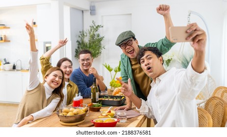 Group of Cheerful Asian man and woman friends enjoy dinner party using mobile phone taking selfie together at home. Happy male and female reunion meeting and celebrating on holiday event vacation. - Powered by Shutterstock