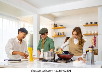 Group Of Cheerful Asian Man And Woman Enjoy Cooking And Talking Together In The Kitchen At Home. Happy People Friends Having Dinner Party Meeting Celebration Event Eating Food On Holiday Vacation