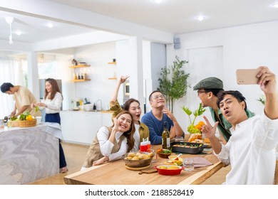Group of Cheerful Asian man and woman friends enjoy dinner party using mobile phone taking selfie together at home. Happy male and female reunion meeting and celebrating on holiday event vacation. - Powered by Shutterstock