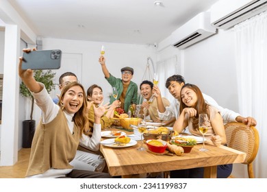 Group of Cheerful Asian man and woman using mobile phone taking selfie together during celebration dinner party at home. Happy people friends enjoy and fun reunion meeting holiday event on vacation. - Powered by Shutterstock