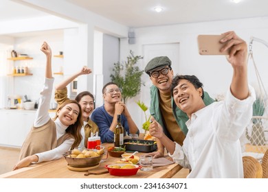 Group of Cheerful Asian man and woman using mobile phone taking selfie together during celebration dinner party at home. Happy people friends enjoy and fun reunion meeting holiday event on vacation. - Powered by Shutterstock