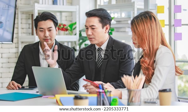 Group of cheerful Asian millennial professional\
successful male businessman and female businesswoman in formal suit\
sitting smiling holding fists up together celebrating customer\
agreement deal done.