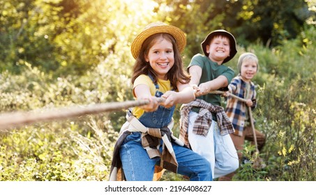 group of cheerful children play outdoors, tug of war in the summer outdoors - Powered by Shutterstock