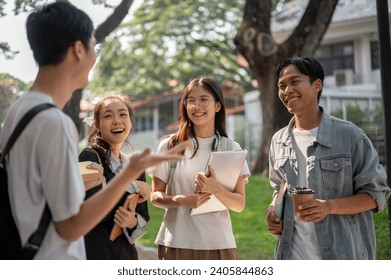 Group of cheerful diverse Asian college students are standing in a campus park and enjoying talking after classes together. Back to school, university life, friendship - Powered by Shutterstock