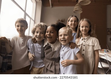 Group of cheerful diverse kids having fun in creative artistic space, hugging, laughing, smiling, looking at camera. Art school pupils, friends, classmates enjoying leisure in classroom - Powered by Shutterstock