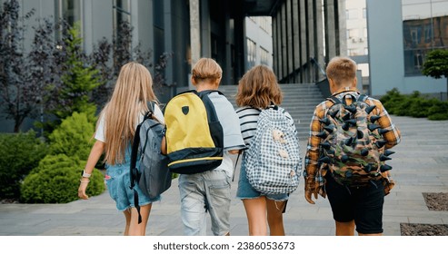 Group of cheerful energetic students child girl boy go to modern campus school with school backpacks. Kids meet each other in front of school. Back to school education kids concept. - Shutterstock ID 2386053673