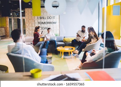 Group Of Cheerful And Friendly Coworkers Talking And Having Fun While Sitting Together In Bright Design Office And Sharing Ideas