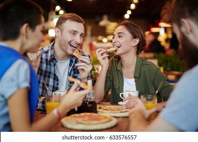 Group of cheerful friends eating delicious pizza and chatting animatedly while gathered in lovely small cafe, waist-up portrait - Powered by Shutterstock