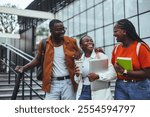 A group of cheerful friends enjoy a walk on campus, engaging in conversation while carrying laptops and notebooks. They are relaxed and enjoying each other